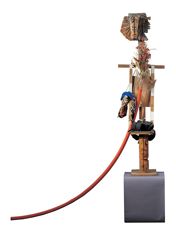 A  stylized figure sculpture made from various found objects and carved wood.