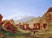 Landscape of a circular wall surrounding arched ruins with mountains and blue sky in background and lone figure in foreground.